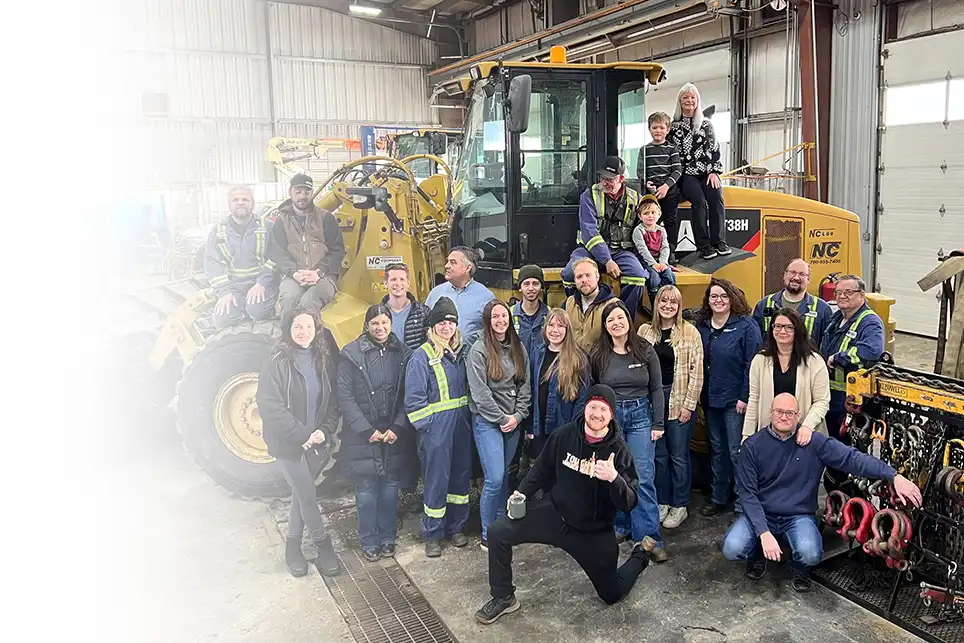 The NC Equipment team stands in front of and on top of a bulldozer tracker along with two members of the TSG team.