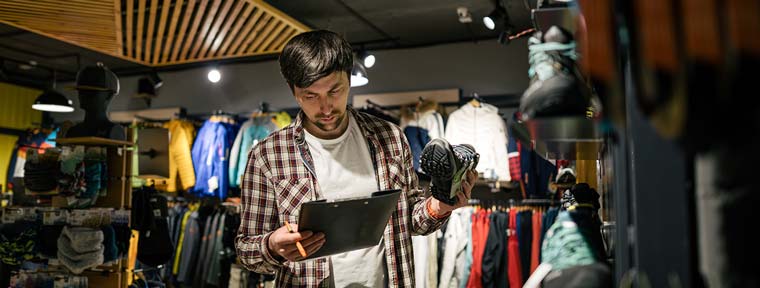 Store employee checking product inventory on tablet.